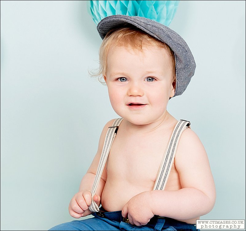 baby photos bolton, childrens portraits bolton, baby in flat cap, braces,