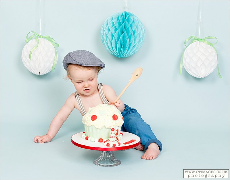 baby boy cake smash, flat cap, wooden spoon, boy in braces,